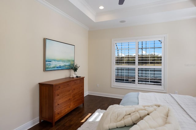 bedroom featuring a tray ceiling, crown molding, ceiling fan, and dark wood-type flooring