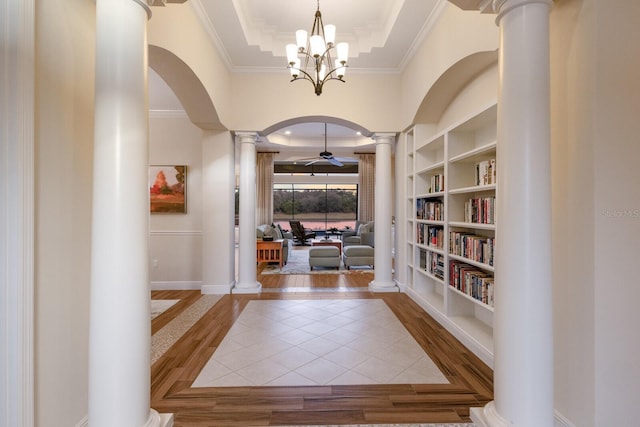 interior space featuring a tray ceiling, crown molding, hardwood / wood-style floors, and ceiling fan with notable chandelier