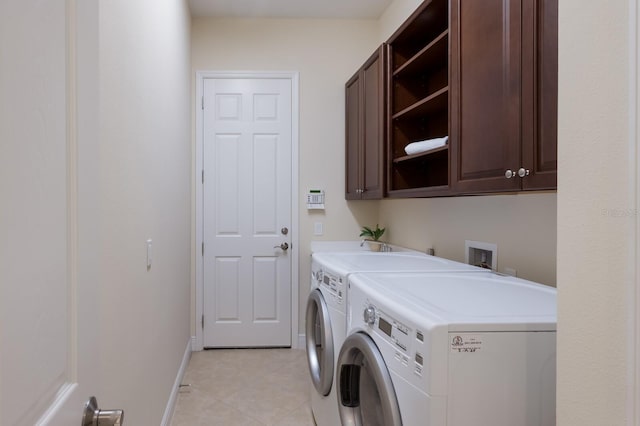 laundry room with washer and clothes dryer, light tile patterned flooring, and cabinets