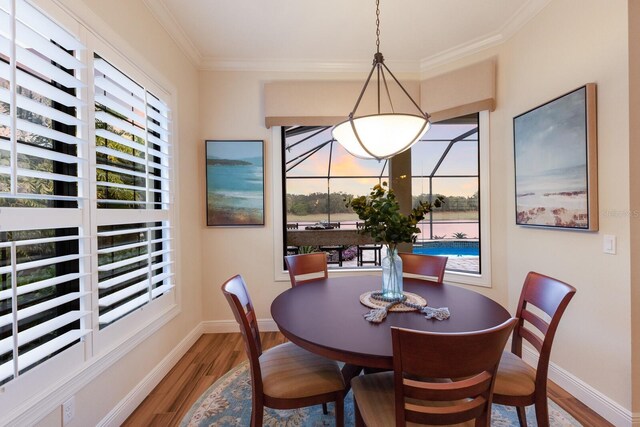 dining space with wood-type flooring, ornamental molding, and a water view