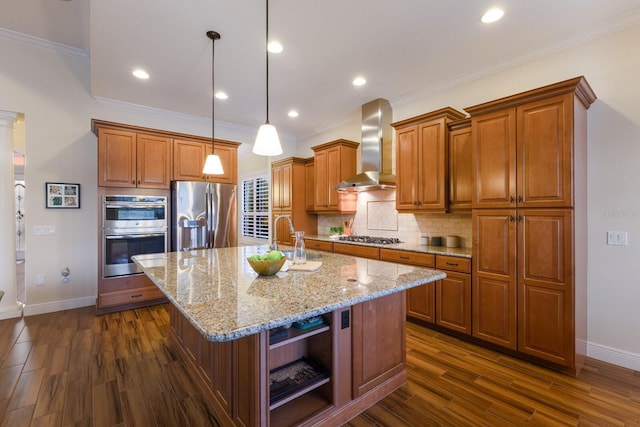 kitchen with sink, a kitchen island with sink, hanging light fixtures, stainless steel appliances, and wall chimney exhaust hood