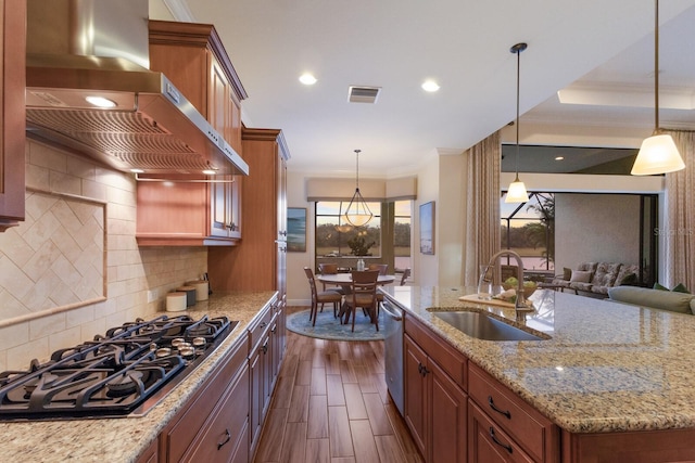 kitchen with pendant lighting, ventilation hood, sink, stainless steel appliances, and light stone countertops