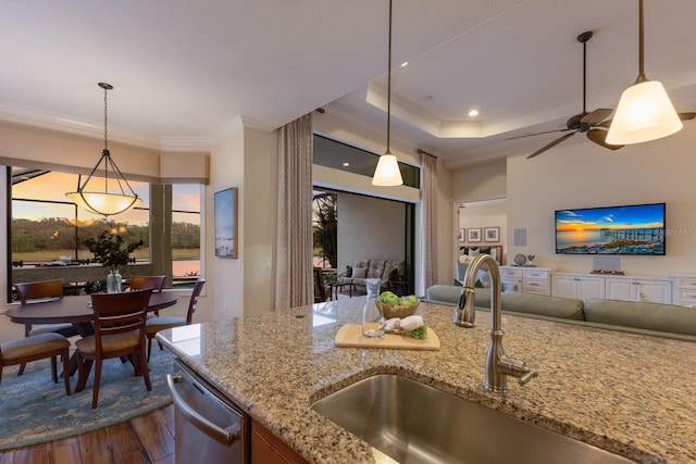 kitchen featuring sink, light stone counters, hanging light fixtures, stainless steel dishwasher, and dark hardwood / wood-style flooring