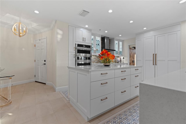 kitchen with wall chimney exhaust hood, stainless steel double oven, white cabinets, a center island, and hanging light fixtures