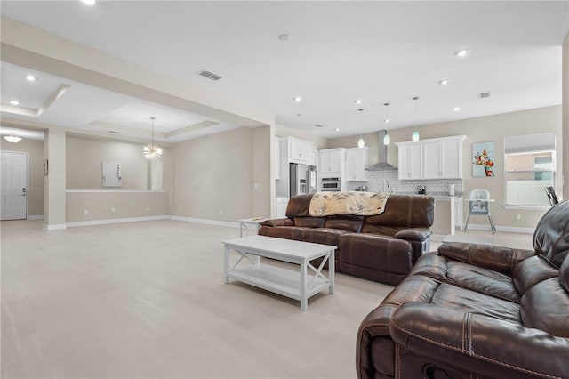 living room with a raised ceiling, sink, and an inviting chandelier