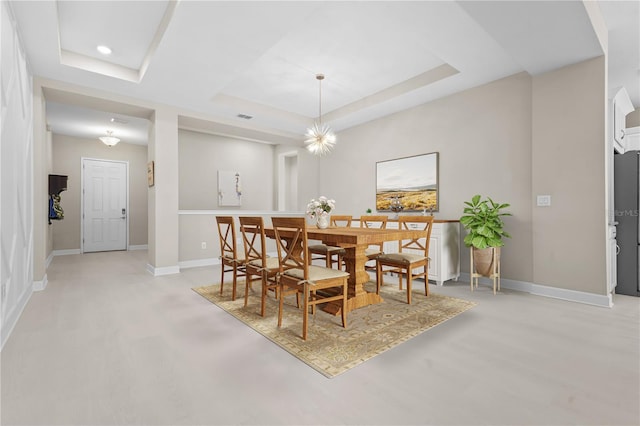 dining area featuring a notable chandelier and a raised ceiling