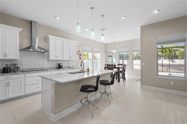 kitchen featuring white cabinets, wall chimney exhaust hood, and sink