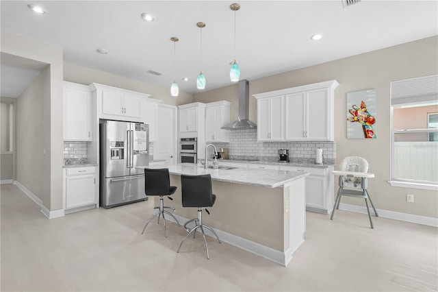 kitchen featuring white cabinetry, wall chimney exhaust hood, pendant lighting, and appliances with stainless steel finishes