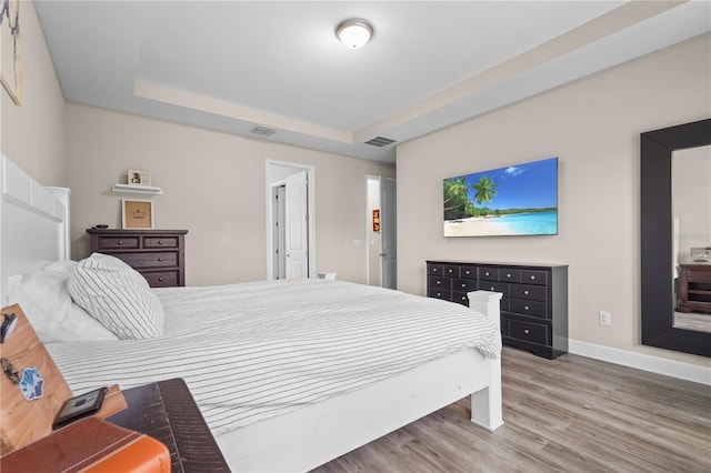 bedroom with hardwood / wood-style flooring and a raised ceiling