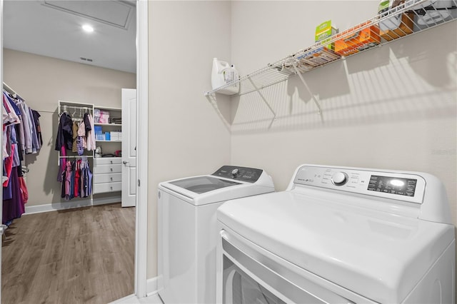 clothes washing area with hardwood / wood-style flooring and independent washer and dryer