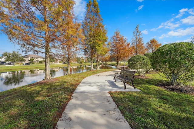 surrounding community with a water view and a yard