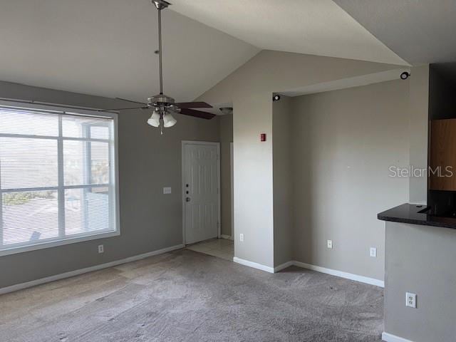 unfurnished living room with light carpet, plenty of natural light, ceiling fan, and lofted ceiling