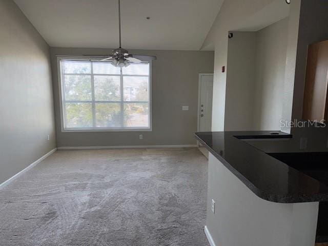 unfurnished dining area featuring ceiling fan, lofted ceiling, and light carpet