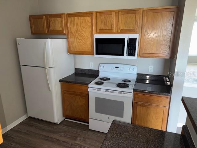 kitchen with white appliances and dark wood-type flooring