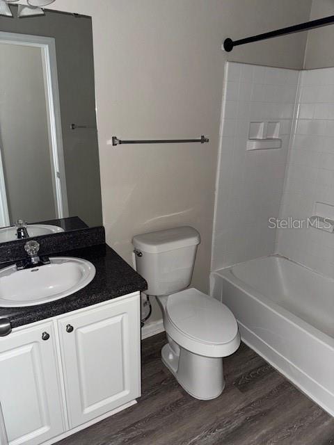 full bathroom featuring hardwood / wood-style floors, vanity, toilet, and bathing tub / shower combination