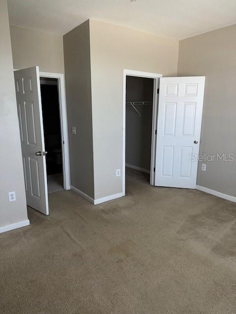 unfurnished bedroom with carpet flooring, a walk in closet, and a closet