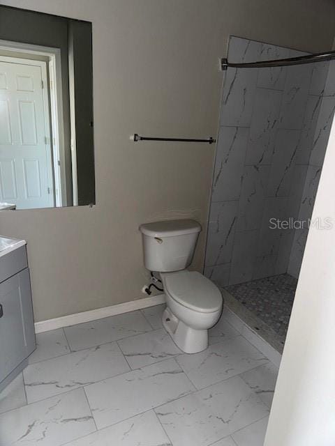 bathroom with toilet, vanity, and tiled shower