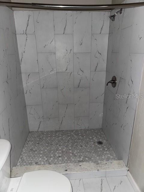 bathroom featuring a tile shower and toilet