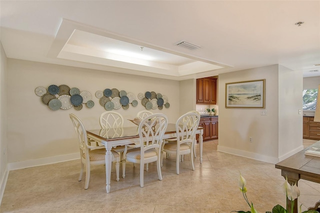 dining space with light tile patterned floors and a tray ceiling