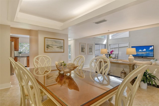 dining space with light tile patterned floors and a tray ceiling