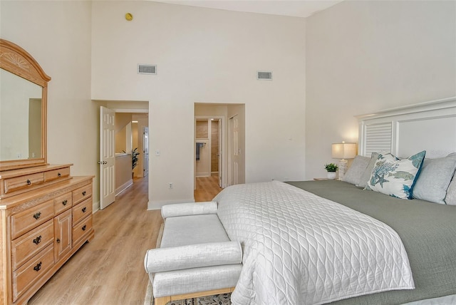 bedroom with a high ceiling and light wood-type flooring