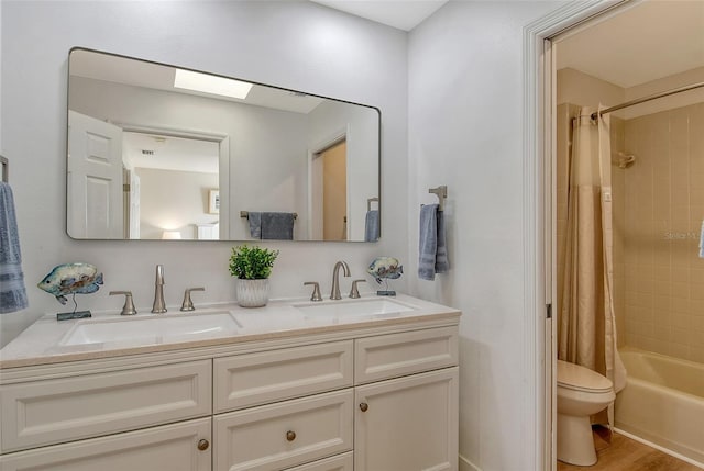 full bathroom featuring a skylight, vanity, wood-type flooring, toilet, and shower / bath combo with shower curtain