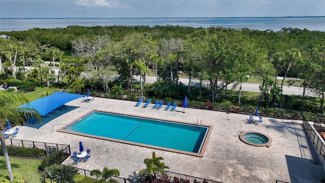 view of swimming pool with a hot tub, a patio, and a water view