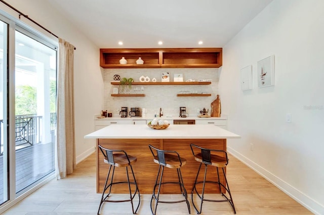 bar featuring white cabinetry, decorative backsplash, and light wood-type flooring