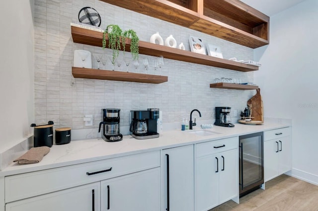 bar with wine cooler, backsplash, light stone counters, and white cabinets