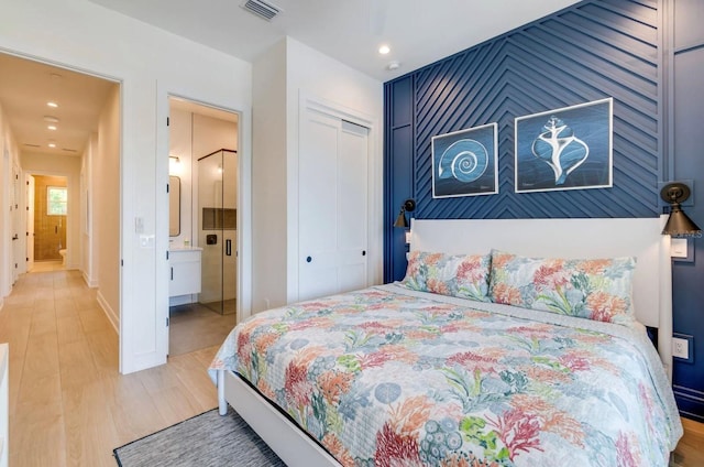 bedroom with a closet, connected bathroom, and light hardwood / wood-style flooring