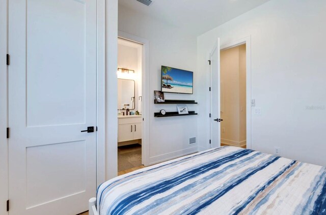 bedroom with ensuite bathroom and hardwood / wood-style floors