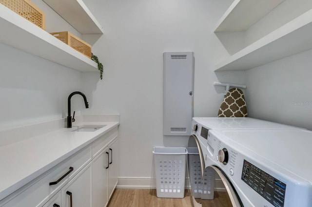 washroom featuring cabinets, washing machine and dryer, sink, and light wood-type flooring