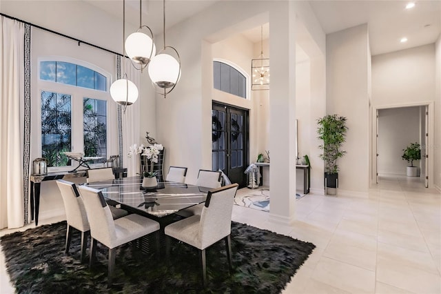 dining room featuring a notable chandelier, a towering ceiling, and light tile patterned floors