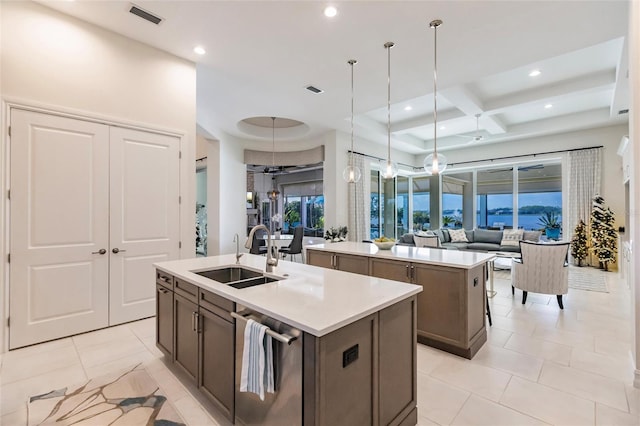 kitchen featuring coffered ceiling, a center island with sink, sink, beamed ceiling, and decorative light fixtures