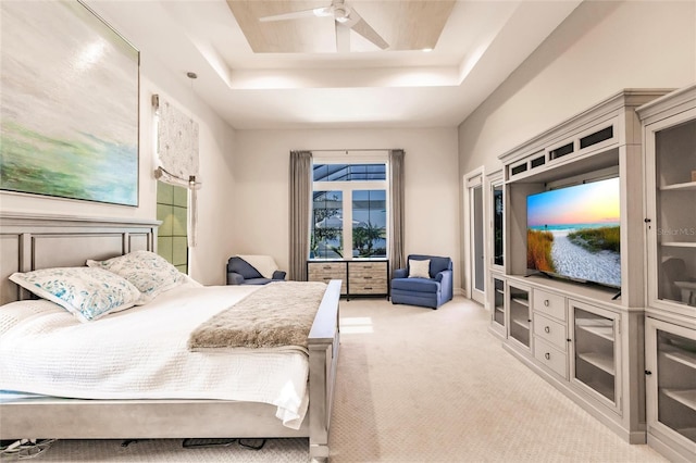 bedroom with a raised ceiling, ceiling fan, and light carpet