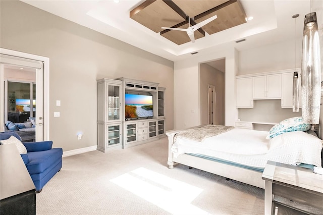 bedroom featuring ceiling fan, light carpet, and a tray ceiling