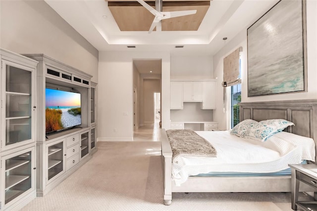 carpeted bedroom with ceiling fan and a raised ceiling