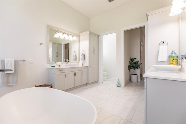 bathroom with vanity, a bath, and toilet