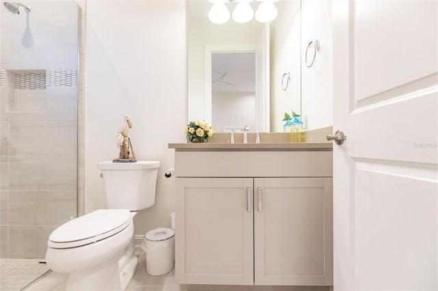 bathroom featuring tile patterned flooring, vanity, toilet, and tiled shower