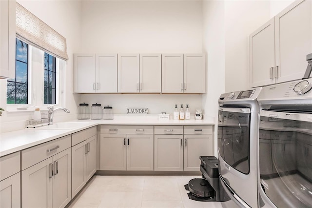 clothes washing area with washer and dryer, light tile patterned flooring, cabinets, and sink