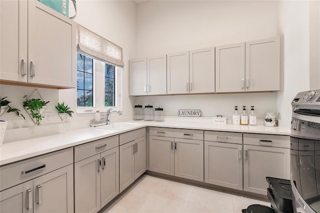 kitchen featuring gray cabinets, light tile patterned floors, and sink