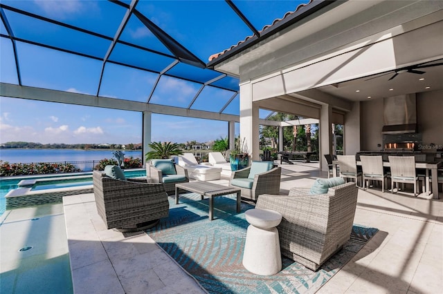 view of patio / terrace with a lanai, a pool with hot tub, exterior bar, ceiling fan, and a water view