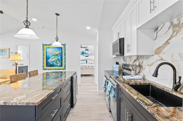 kitchen featuring sink, tasteful backsplash, decorative light fixtures, white cabinets, and appliances with stainless steel finishes