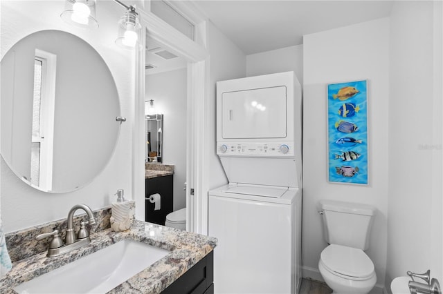 bathroom with vanity, stacked washer and clothes dryer, and toilet