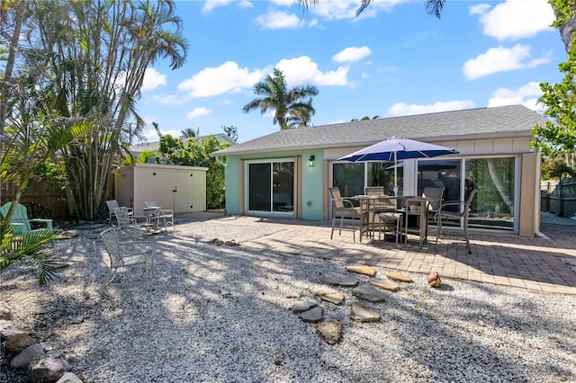 rear view of property featuring a storage unit and a patio