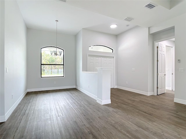 empty room featuring dark wood-type flooring and an inviting chandelier