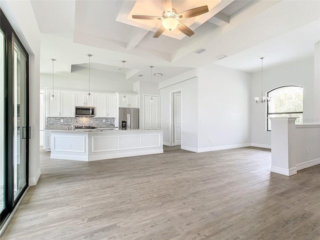 unfurnished living room with beamed ceiling, ceiling fan with notable chandelier, light hardwood / wood-style flooring, and sink