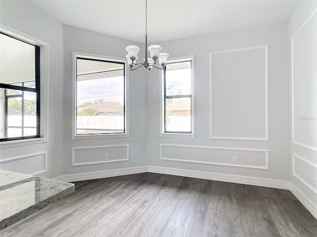 unfurnished dining area featuring a healthy amount of sunlight, dark hardwood / wood-style floors, and a notable chandelier