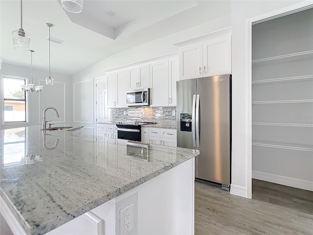 kitchen featuring white cabinetry, sink, hanging light fixtures, stainless steel appliances, and backsplash