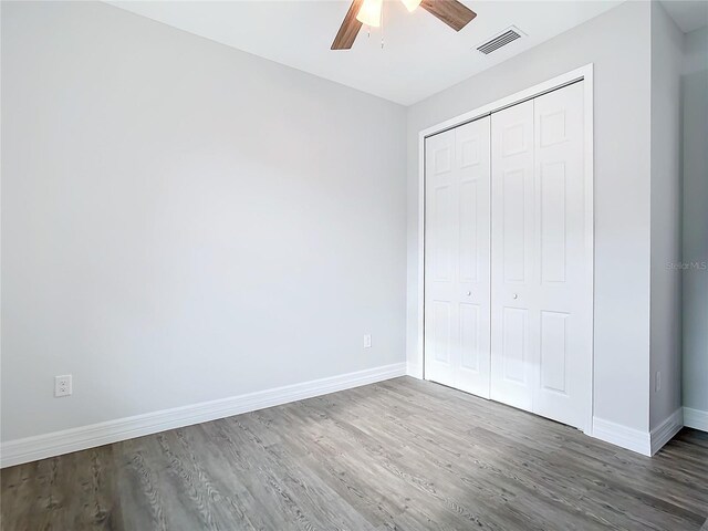 unfurnished bedroom featuring dark hardwood / wood-style flooring, a closet, and ceiling fan